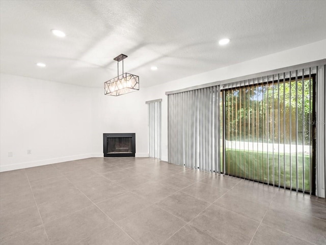 unfurnished living room featuring a notable chandelier, a textured ceiling, and light tile patterned flooring