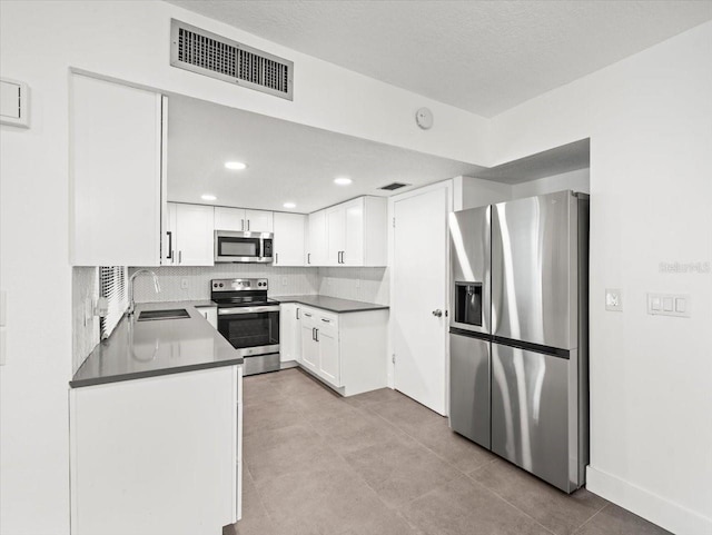 kitchen featuring white cabinetry, tasteful backsplash, light tile patterned floors, stainless steel appliances, and sink