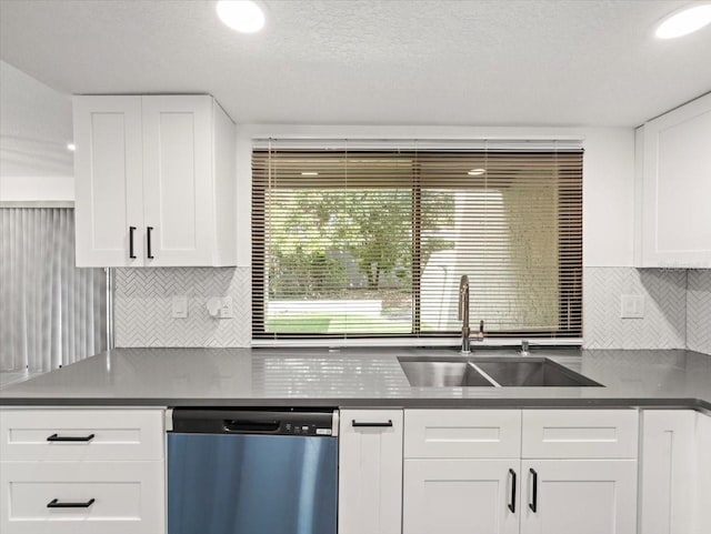 kitchen with a textured ceiling, backsplash, stainless steel dishwasher, sink, and white cabinetry