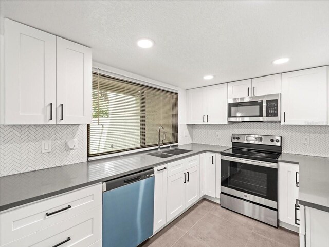 kitchen featuring white cabinetry, backsplash, light tile patterned floors, sink, and appliances with stainless steel finishes