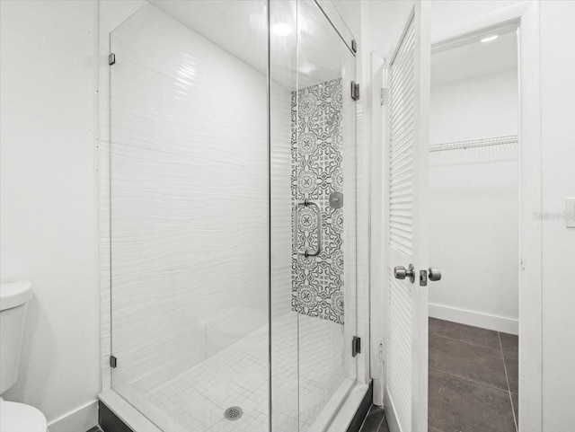 bathroom featuring tile patterned flooring, toilet, and an enclosed shower