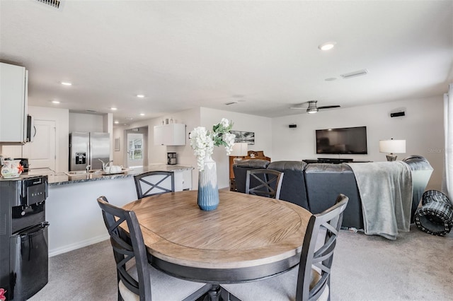 dining space featuring ceiling fan and light colored carpet