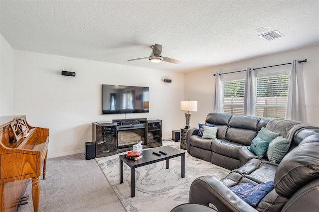 carpeted living room featuring ceiling fan and a textured ceiling