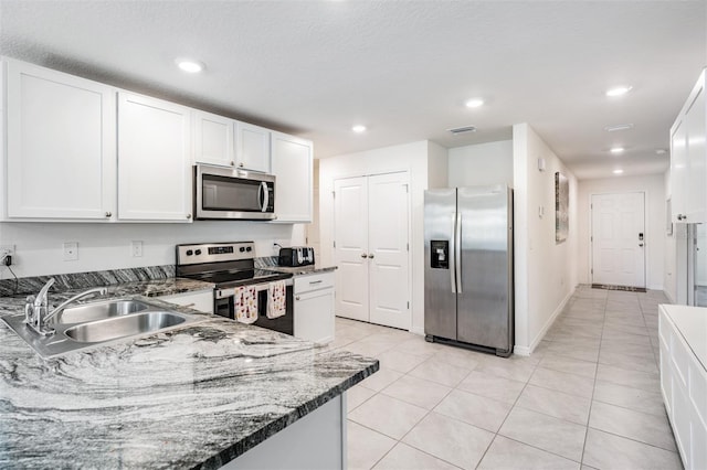 kitchen featuring white cabinets, stone countertops, light tile patterned floors, sink, and stainless steel appliances