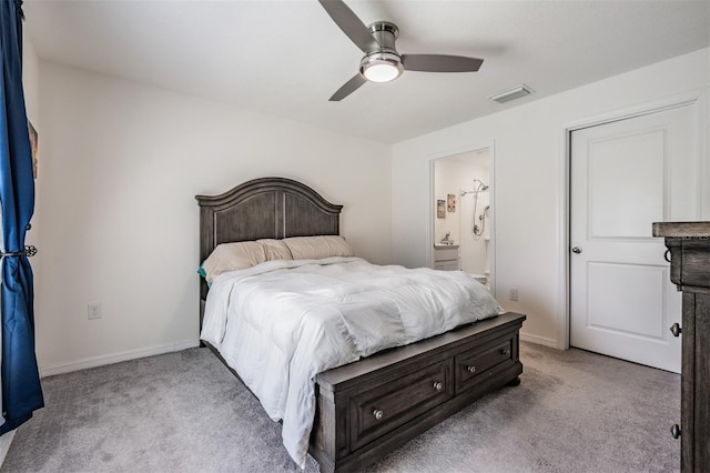 bedroom featuring ceiling fan, light colored carpet, and ensuite bath