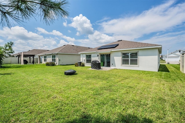 back of property featuring solar panels and a yard