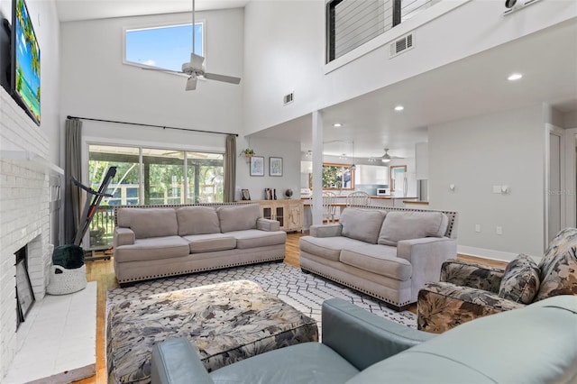 living room with a fireplace, light wood-type flooring, a wealth of natural light, and ceiling fan