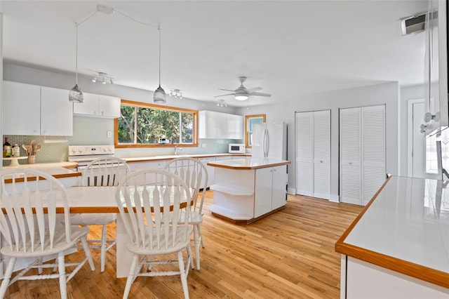 kitchen with white cabinetry, white appliances, light hardwood / wood-style flooring, a center island, and ceiling fan