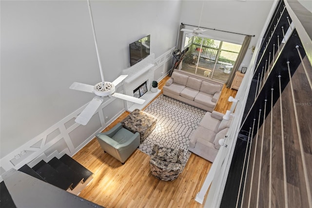 living room with a high ceiling, hardwood / wood-style floors, and ceiling fan