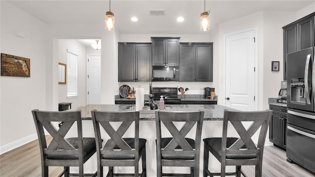 kitchen with black appliances, a kitchen breakfast bar, hanging light fixtures, and a kitchen island with sink