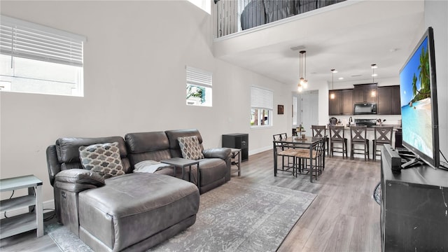 living room with baseboards, a high ceiling, and light wood-style floors