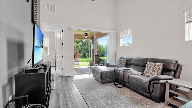 living room featuring hardwood / wood-style floors, a towering ceiling, and ceiling fan