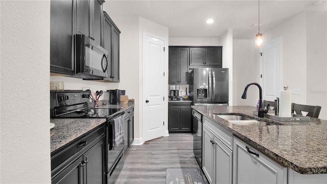 kitchen with black appliances, sink, a kitchen island with sink, and dark stone counters