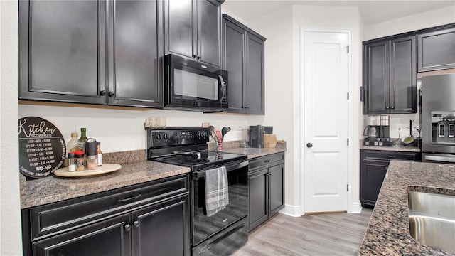 kitchen with dark stone countertops, light hardwood / wood-style flooring, and black appliances