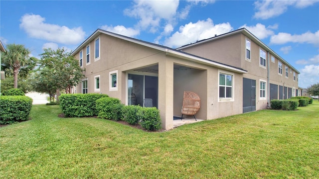 back of house with a lawn and stucco siding