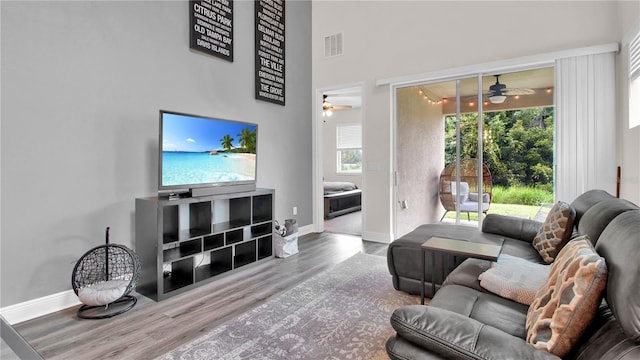 living room featuring baseboards, visible vents, a wealth of natural light, and wood finished floors