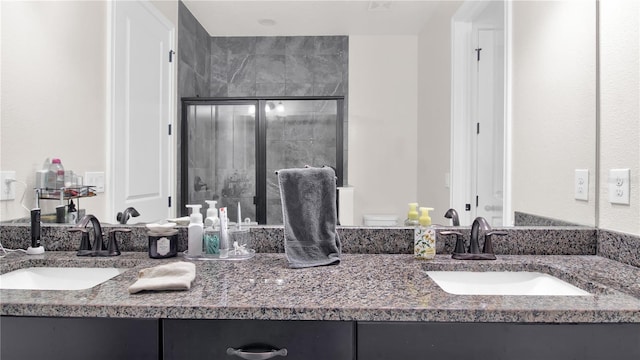 bathroom with a sink, a shower stall, and double vanity