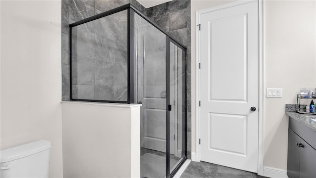 bathroom with toilet, a shower stall, baseboards, and vanity