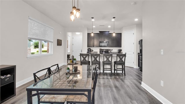 dining area featuring baseboards, wood finished floors, and recessed lighting