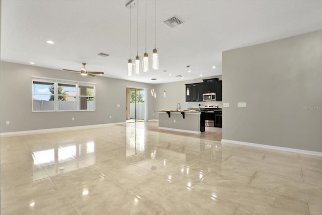 interior space featuring stainless steel appliances, an island with sink, pendant lighting, light tile patterned floors, and ceiling fan