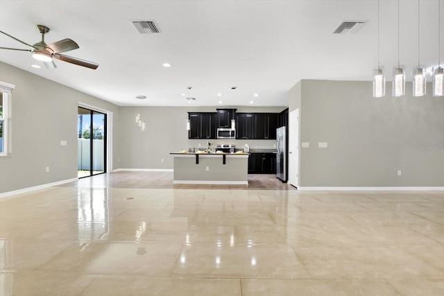 kitchen featuring stainless steel appliances, decorative light fixtures, a center island with sink, and light tile patterned floors