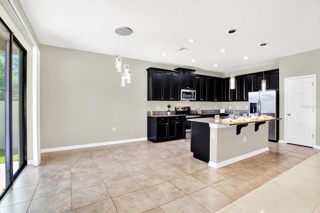 kitchen featuring appliances with stainless steel finishes, pendant lighting, an island with sink, and a wealth of natural light