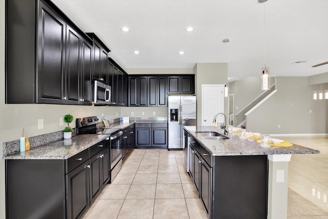 kitchen featuring light tile patterned flooring, sink, light stone counters, an island with sink, and stainless steel appliances