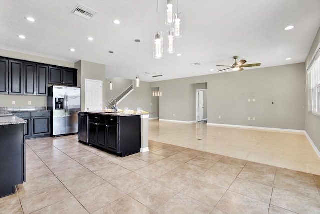 kitchen featuring decorative light fixtures, dishwashing machine, stainless steel refrigerator with ice dispenser, light tile patterned floors, and a center island with sink