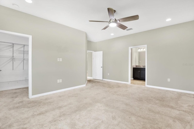 unfurnished bedroom featuring carpet, ensuite bath, a closet, a spacious closet, and ceiling fan