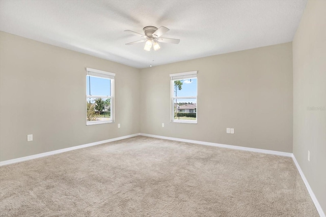 carpeted spare room featuring ceiling fan and a healthy amount of sunlight