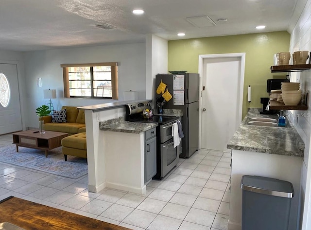 kitchen with double oven range, light stone counters, light tile patterned floors, and sink