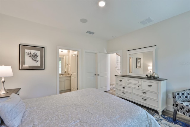 bedroom with connected bathroom and wood-type flooring