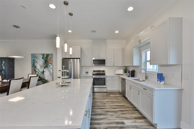 kitchen featuring pendant lighting, tasteful backsplash, light hardwood / wood-style floors, sink, and stainless steel appliances