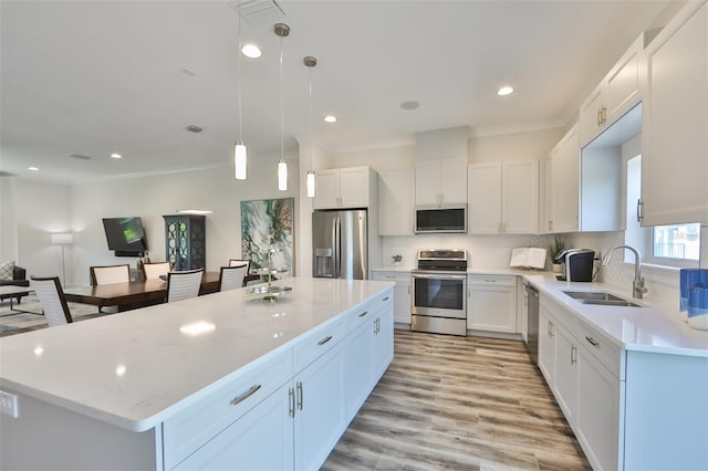 kitchen featuring sink, light wood-type flooring, tasteful backsplash, a kitchen island, and stainless steel appliances