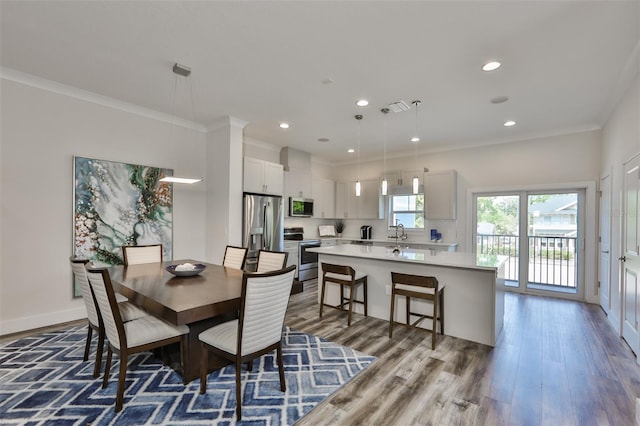 dining space with sink, hardwood / wood-style floors, and ornamental molding