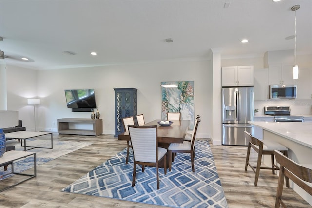 dining area with light hardwood / wood-style floors and ornamental molding