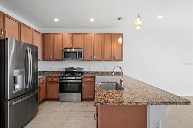 kitchen with hanging light fixtures, appliances with stainless steel finishes, a sink, and brown cabinets