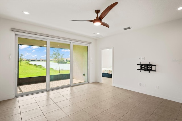 unfurnished room with ceiling fan, light tile patterned floors, and a water view