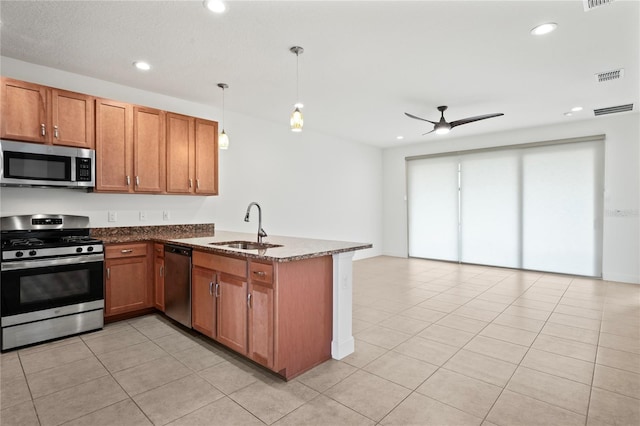 kitchen with brown cabinets, a peninsula, hanging light fixtures, stainless steel appliances, and a sink