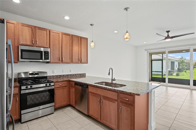 kitchen with pendant lighting, stainless steel appliances, brown cabinetry, a sink, and a peninsula