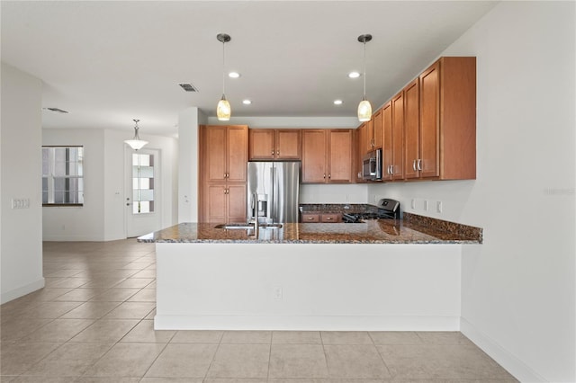 kitchen featuring appliances with stainless steel finishes, brown cabinetry, hanging light fixtures, and a peninsula
