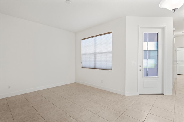 empty room featuring light tile patterned floors and baseboards