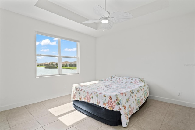 bedroom with ceiling fan, light tile patterned flooring, and a tray ceiling