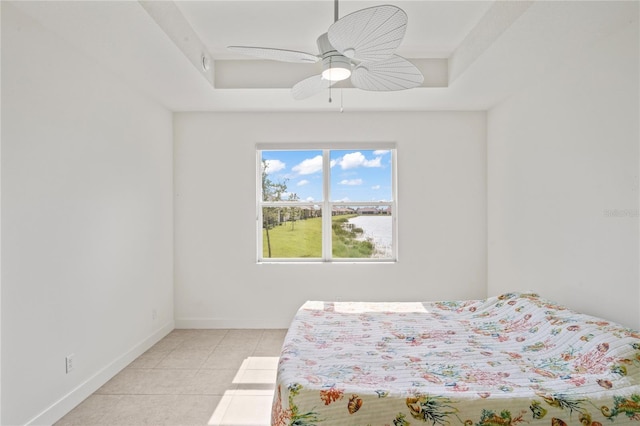 bedroom featuring a ceiling fan, a raised ceiling, baseboards, and light tile patterned floors