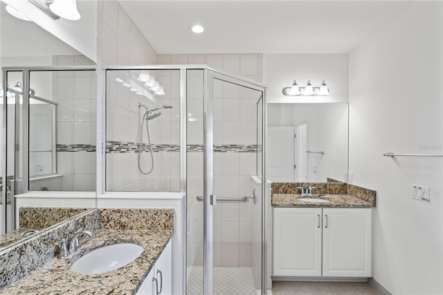 bathroom with a stall shower, two vanities, and a sink