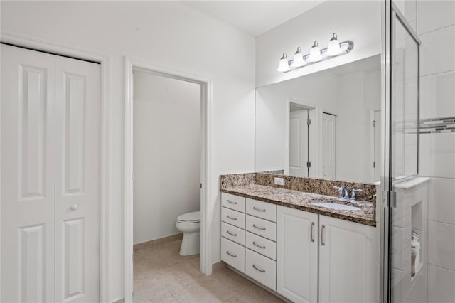 bathroom with toilet, tile patterned flooring, vanity, a shower stall, and a closet