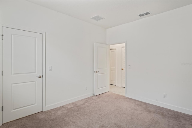unfurnished room with light colored carpet, visible vents, and baseboards