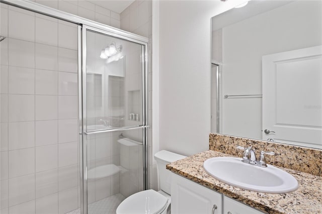 bathroom with toilet, vanity, and a shower with shower door