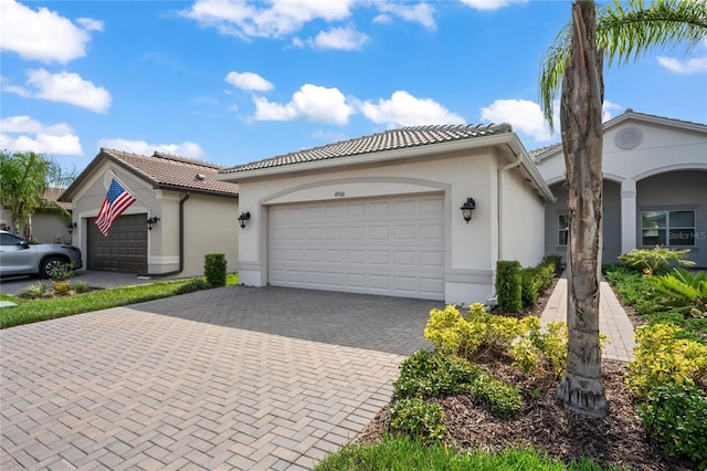 view of front of property featuring a garage, decorative driveway, a tile roof, and stucco siding