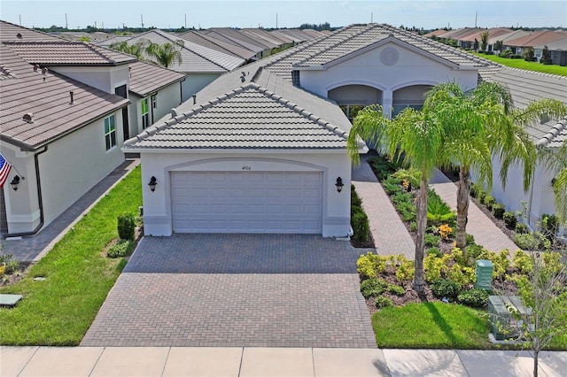 mediterranean / spanish home with a garage, a residential view, decorative driveway, and stucco siding